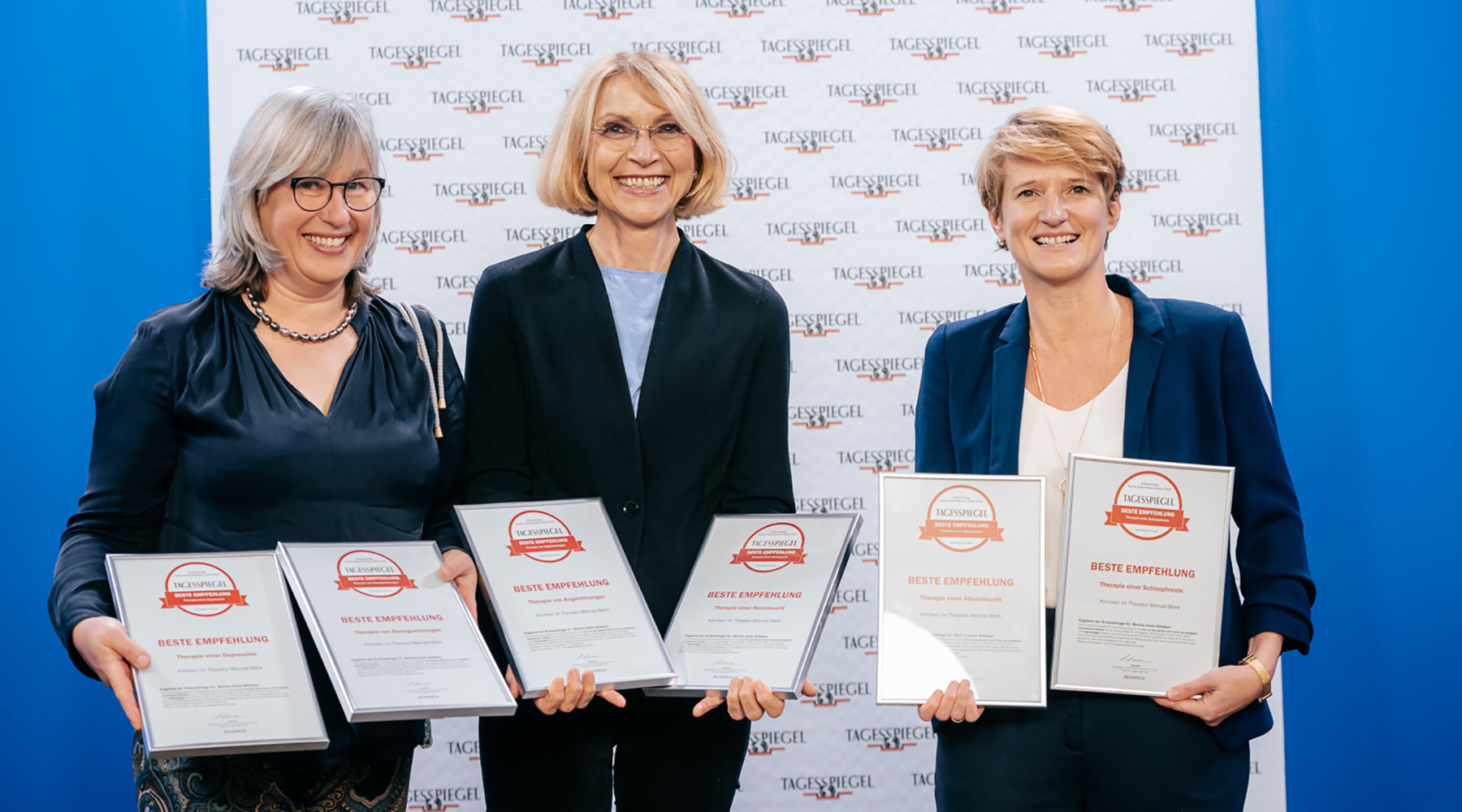Birgit Jänchen-van der Hoofd, Kirsten Suttorp und Lieselotte Mahler halten lächelnd die gerahmten Auszeichnungen des Tagesspiegels für die Kliniken im TWW in den Händen